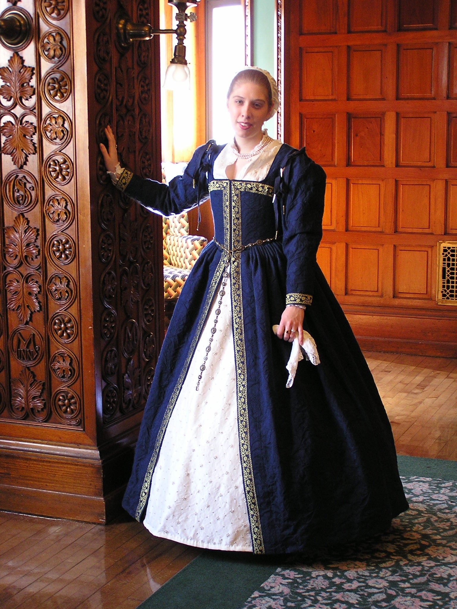 Elizabethan style kirtle. It is worn with a hoop skirt, tie on sleeves, a forepanel skirt, petticoats, a partlet and a coif. She is likely wearing a corset and chemise underneath.